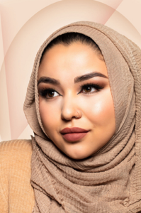 beautiful Arabic woman with makeup long eyelashes and mate liquid lipstick wearing a beige hijab on beige background.