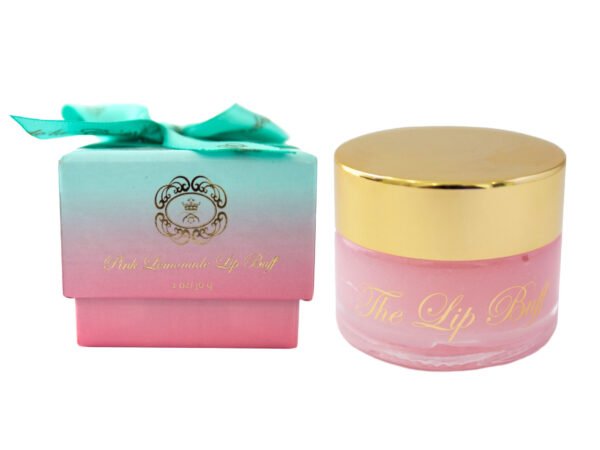 The Lip Buff Pink Lemonade in clear glass jar with glossy gold lid next to a pink and blue box with a ribbon on top